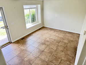 Spacious room featuring neutral-toned walls, large square tile flooring, and a window with a deep sill