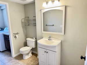 Bathroom featuring a white vanity with integrated sink, chrome faucet, wall-mounted mirror, and overhead vanity lighting