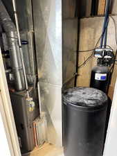 Dedicated utility space featuring a Carrier furnace system, extensive ductwork, water softener, and a black cylindrical tank