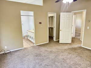 Carpeted interior space featuring a ceiling fan, a walk-in closet, and access to a bathroom with a vanity and toilet