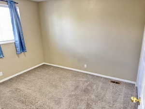 Carpeted interior space with beige wall finishes, white trim, and a window