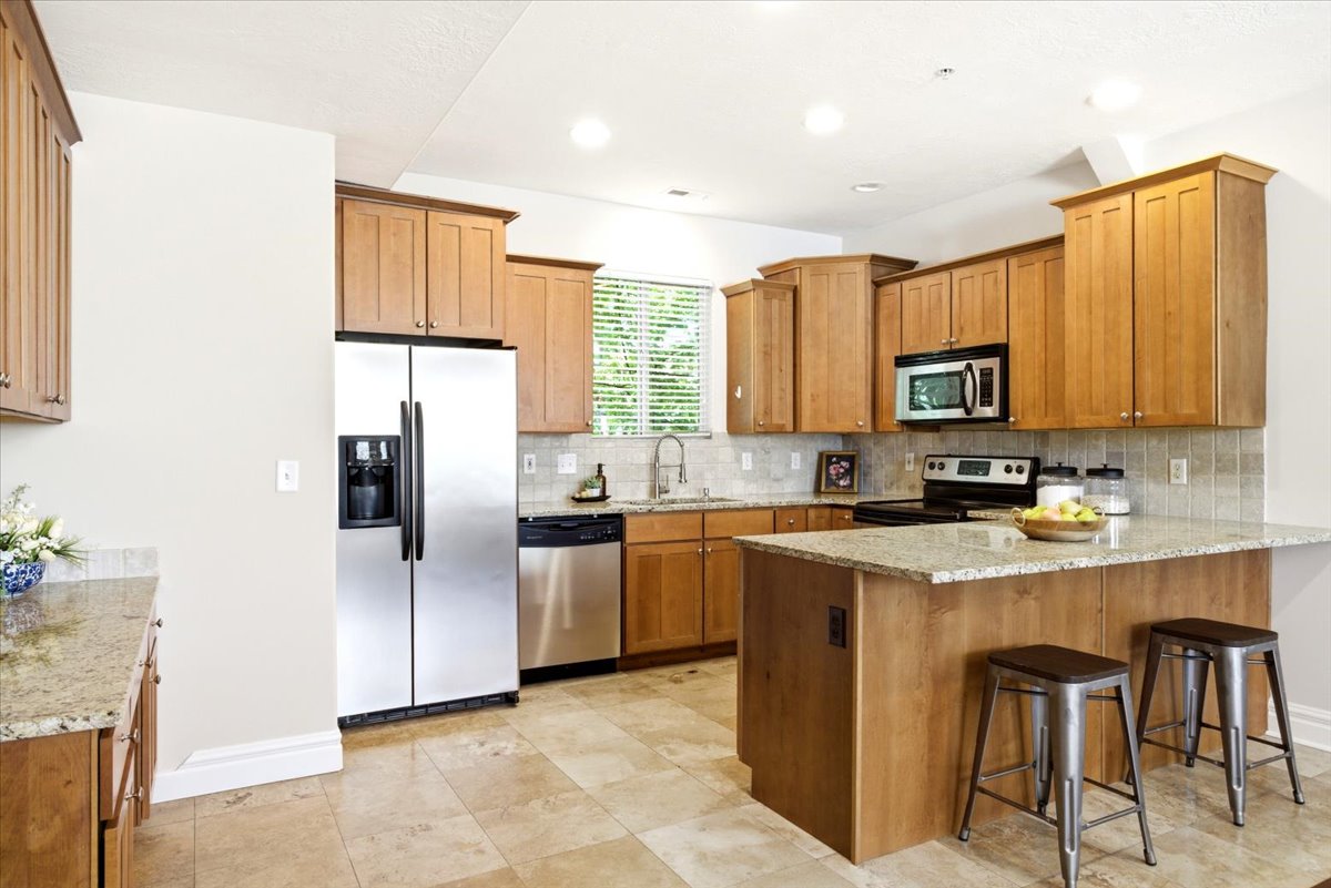Kitchen featuring warm-toned cabinetry, light-toned countertops, and stainless steel appliances