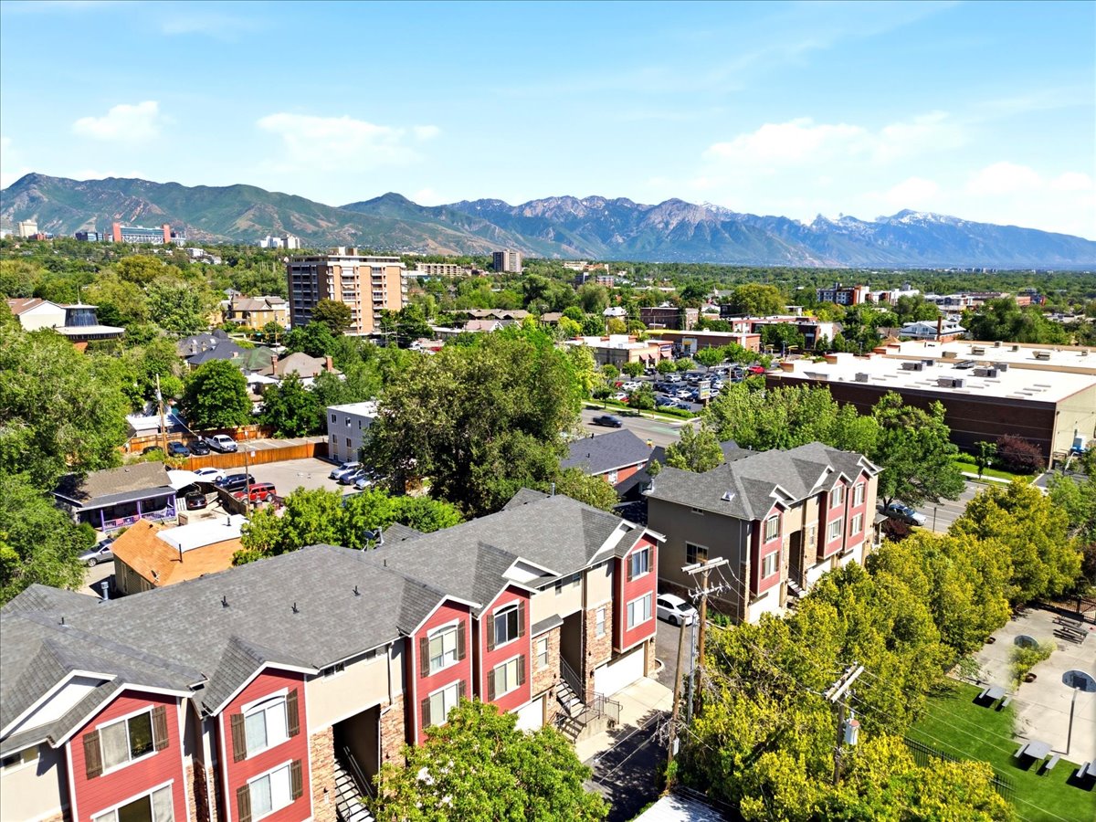 Townhome community featuring multi-story units with red and tan exteriors, dark gray shingle roofs, and individual garage access