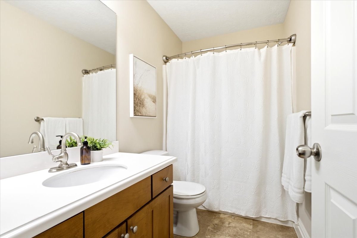 Bathroom featuring wood-finish vanity with white countertop and integrated sink