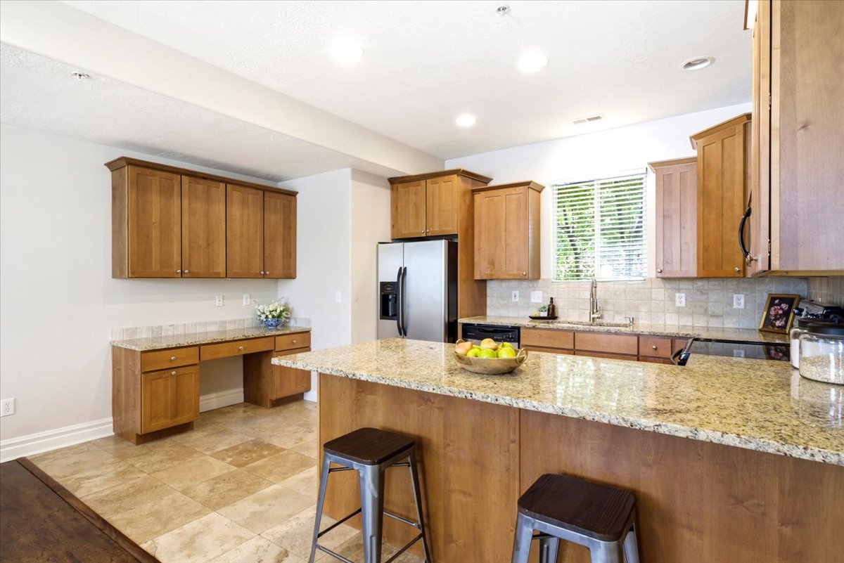 Kitchen featuring light wood cabinetry, stone-finish countertops, stainless steel appliances, and tile flooring