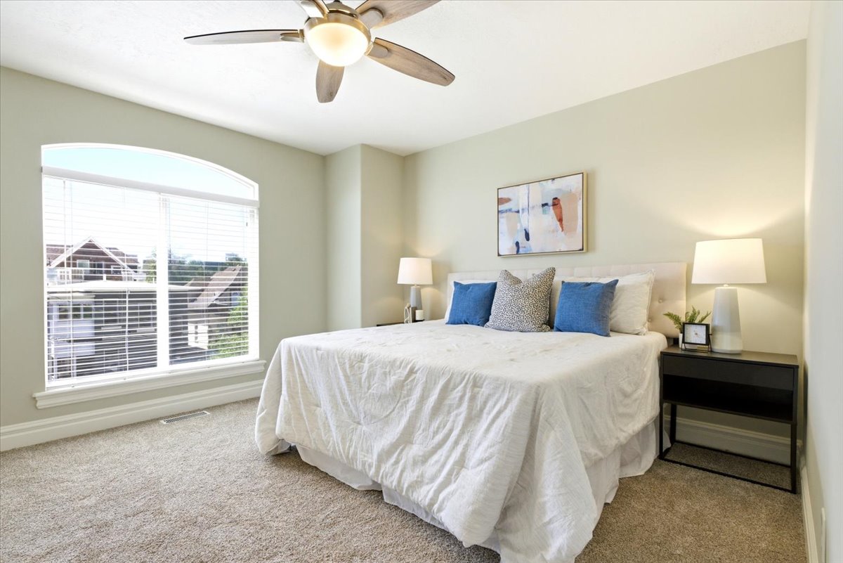 Bedroom featuring an arched window, ceiling fan, and light-colored carpet flooring