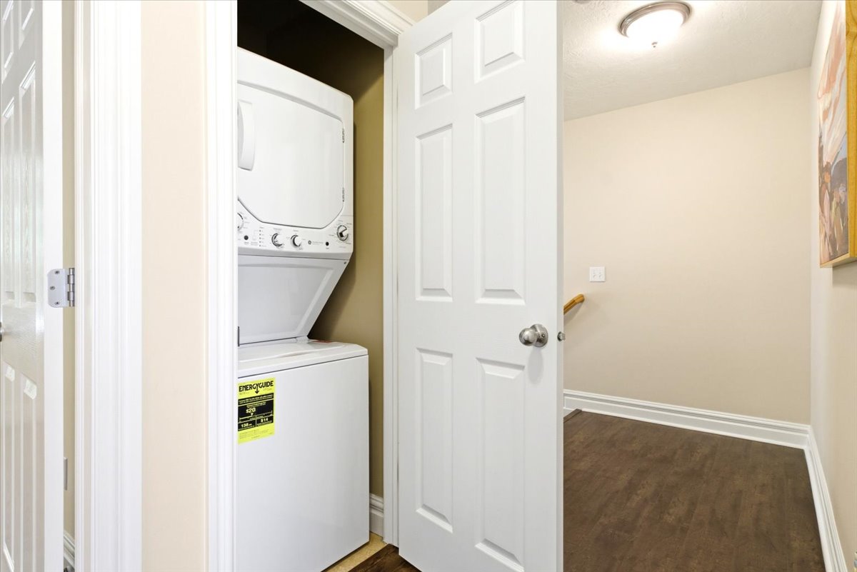 Dedicated laundry closet featuring a white stacked washer and dryer unit