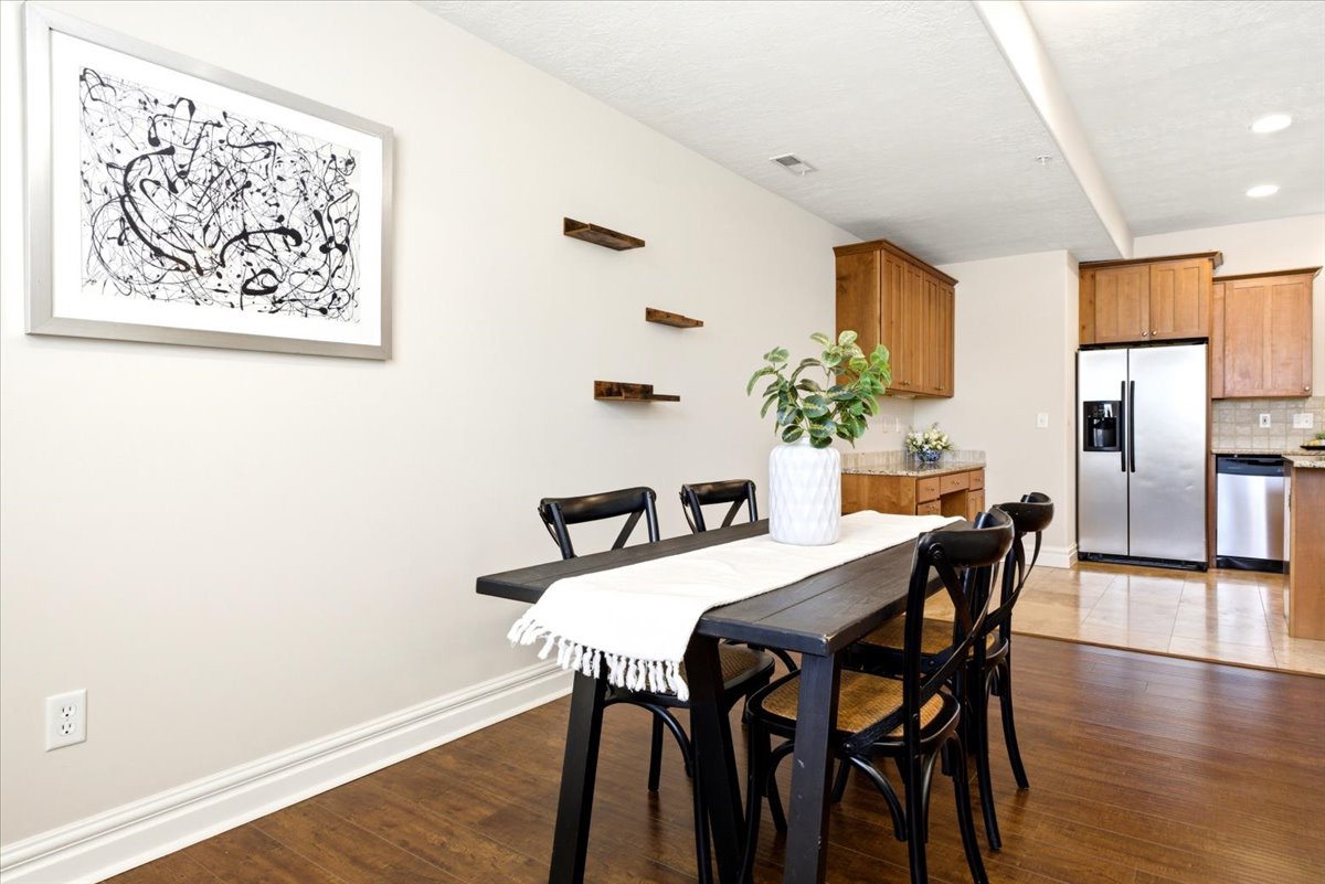 Open-concept dining area featuring wood-finish flooring extending into the kitchen