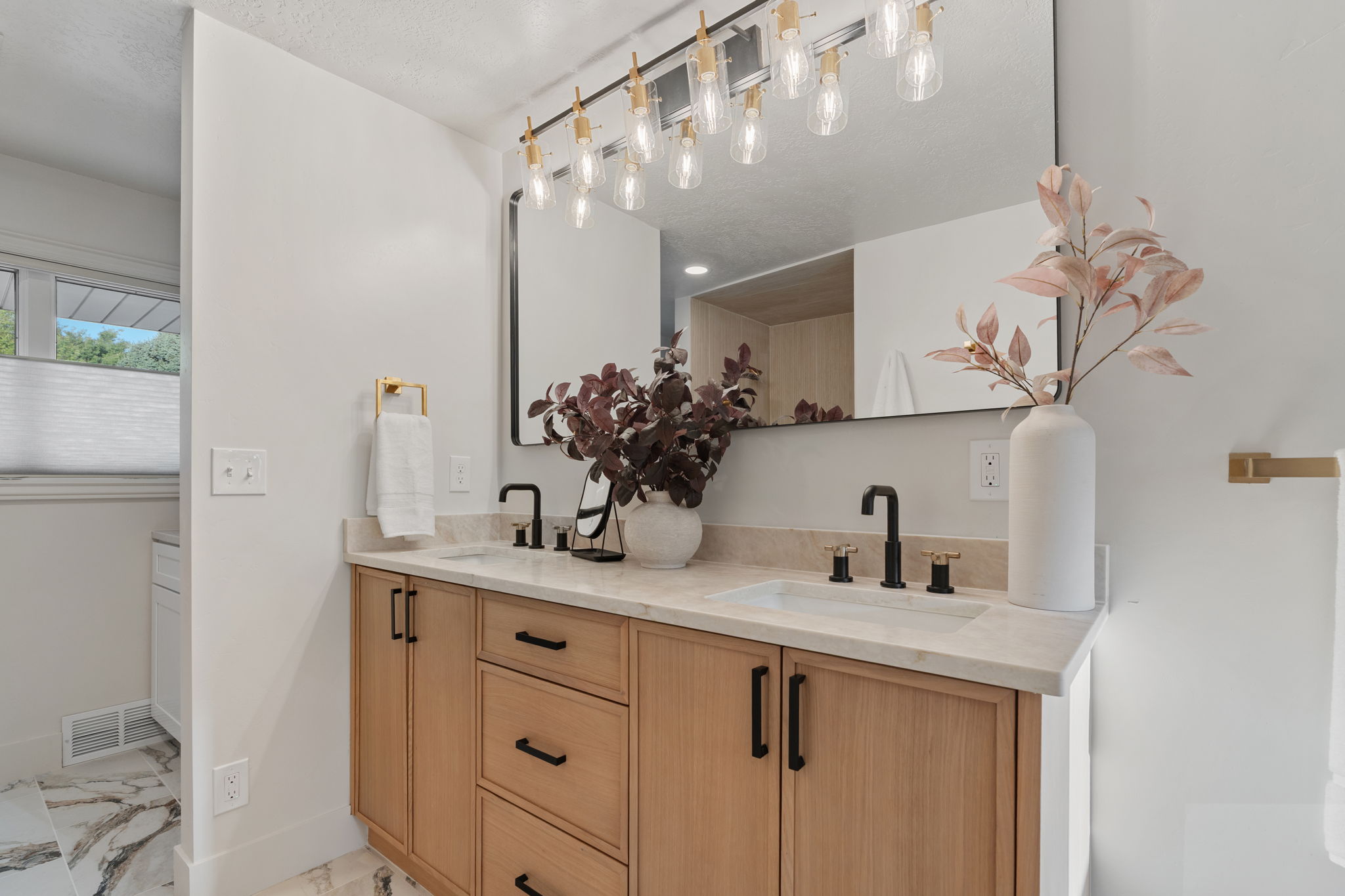 Double vanity with light wood-finish cabinetry and matte black hardware