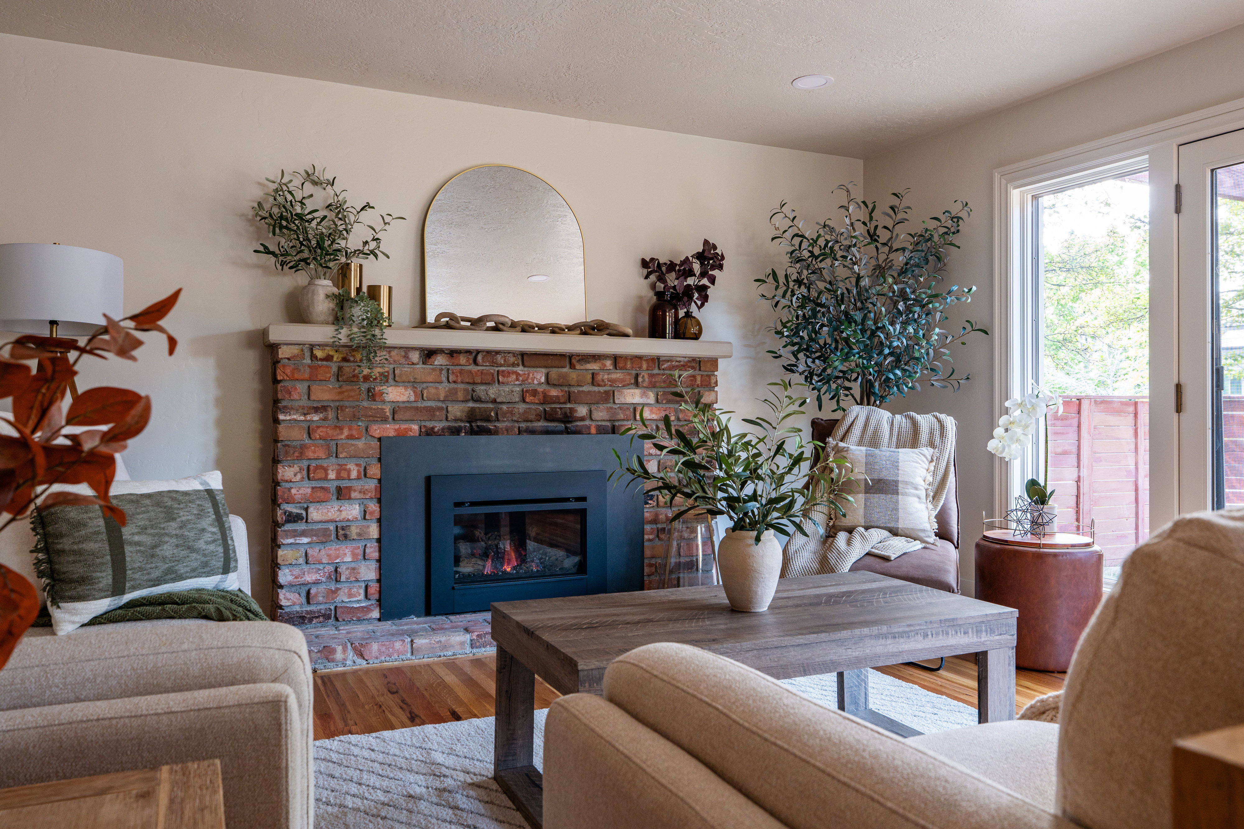 Brick fireplace with a dark-framed insert, flanked by light-toned walls and hardwood flooring