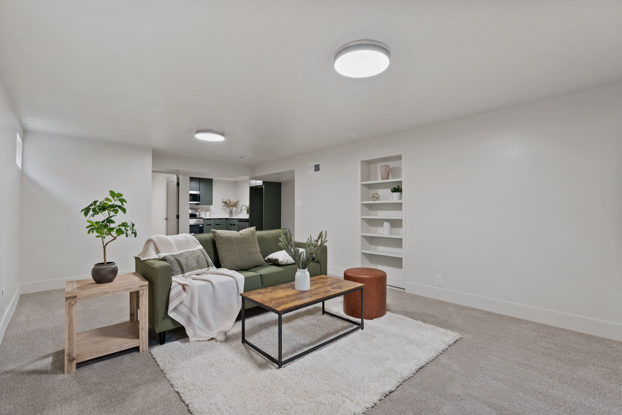 Spacious room featuring light gray carpeting, recessed lighting, and a built-in shelving unit