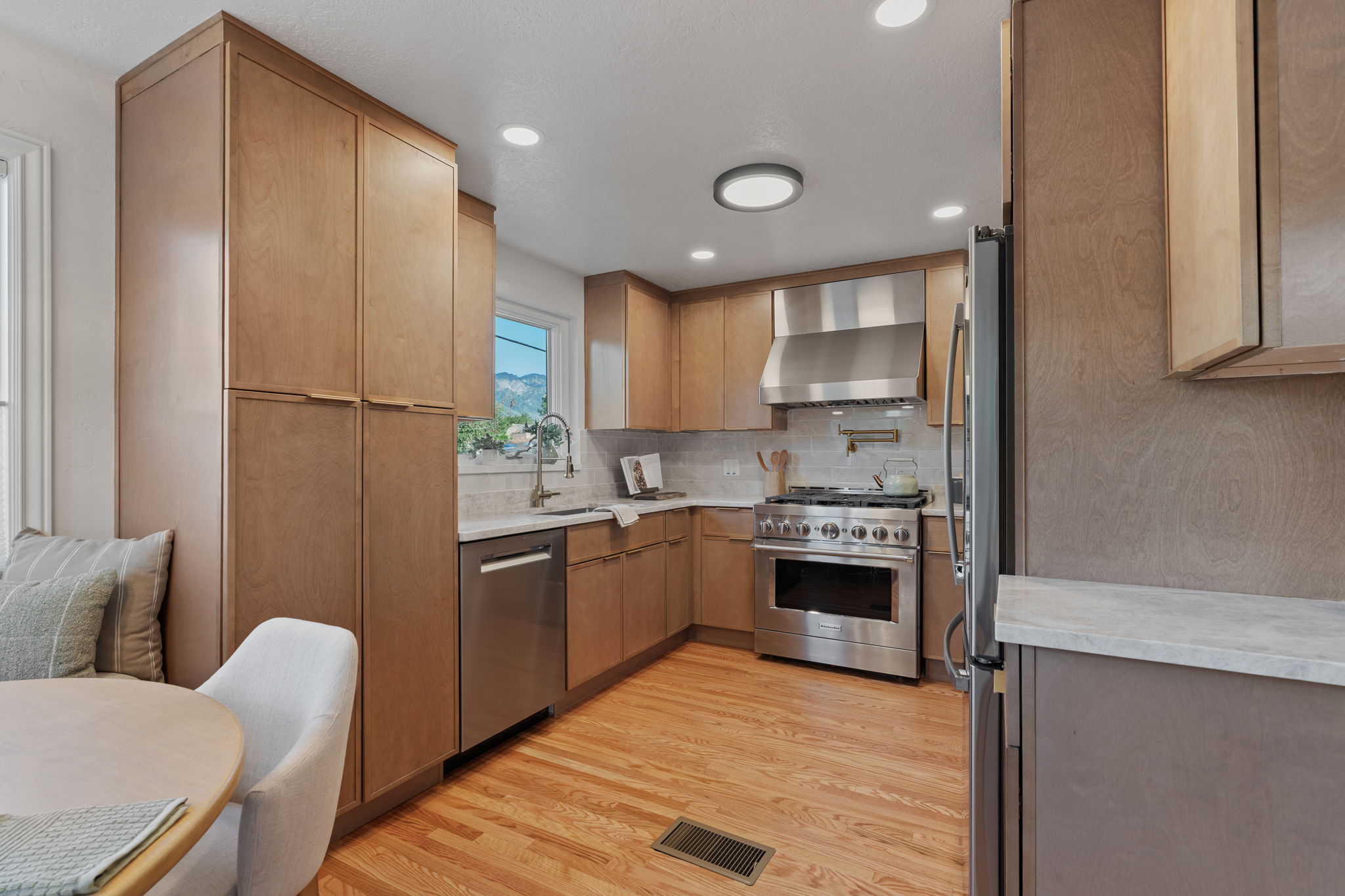 Kitchen featuring wood-finish cabinetry, stainless steel appliances, light countertops, and a tile backsplash