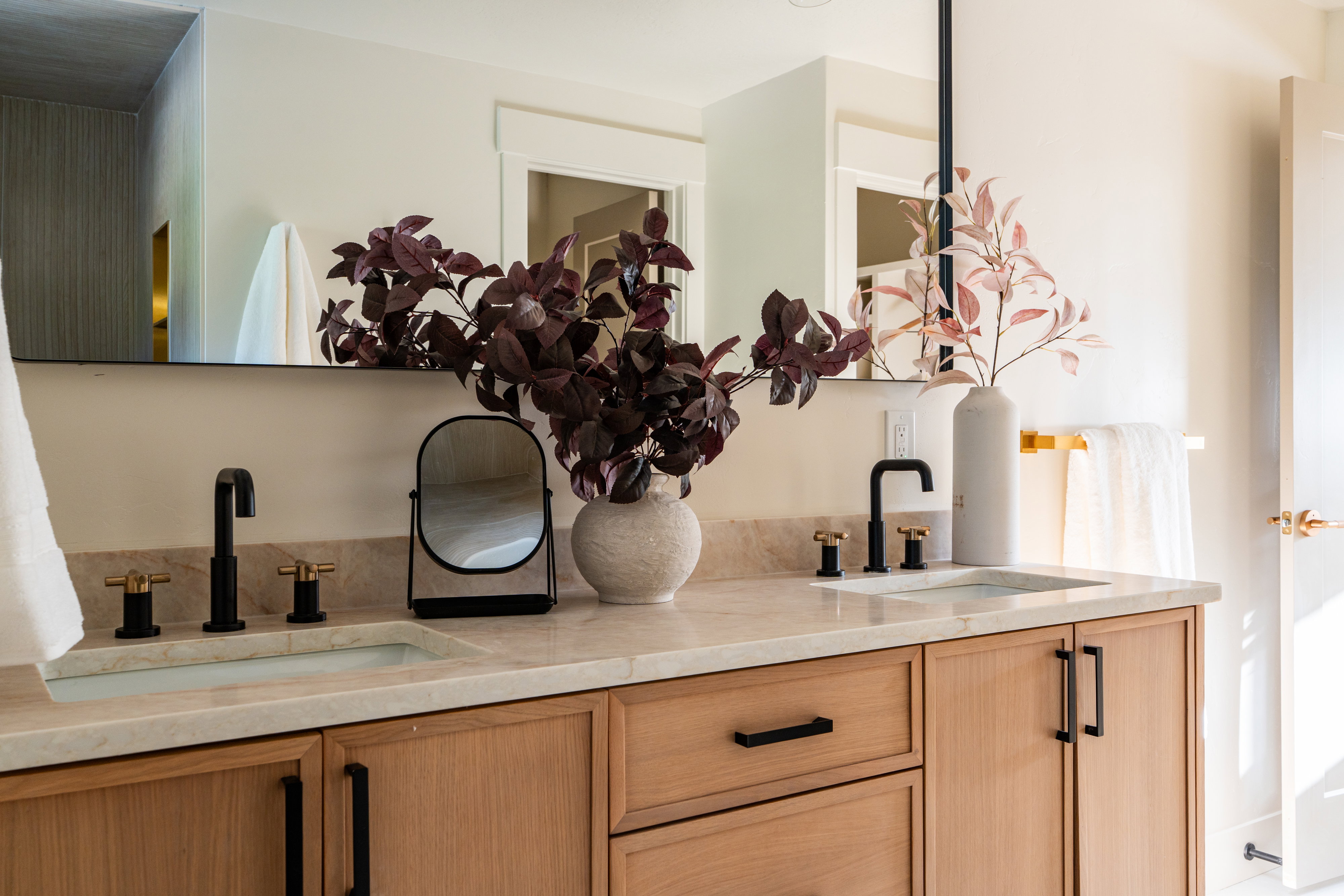 Dual vanity with light wood-finish cabinetry and black hardware
