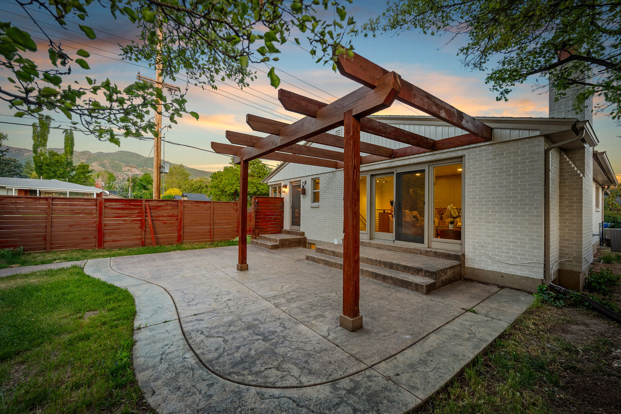 Expansive stamped concrete patio featuring a wood pergola and direct access to interior spaces through sliding glass doors