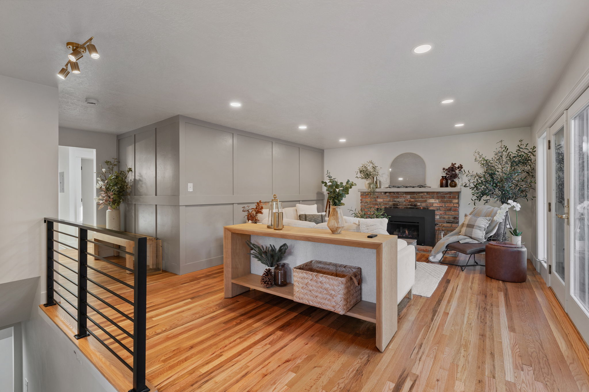 Spacious living area featuring wood-finish flooring, a brick-surround fireplace with arched alcove, recessed lighting, and wall paneling