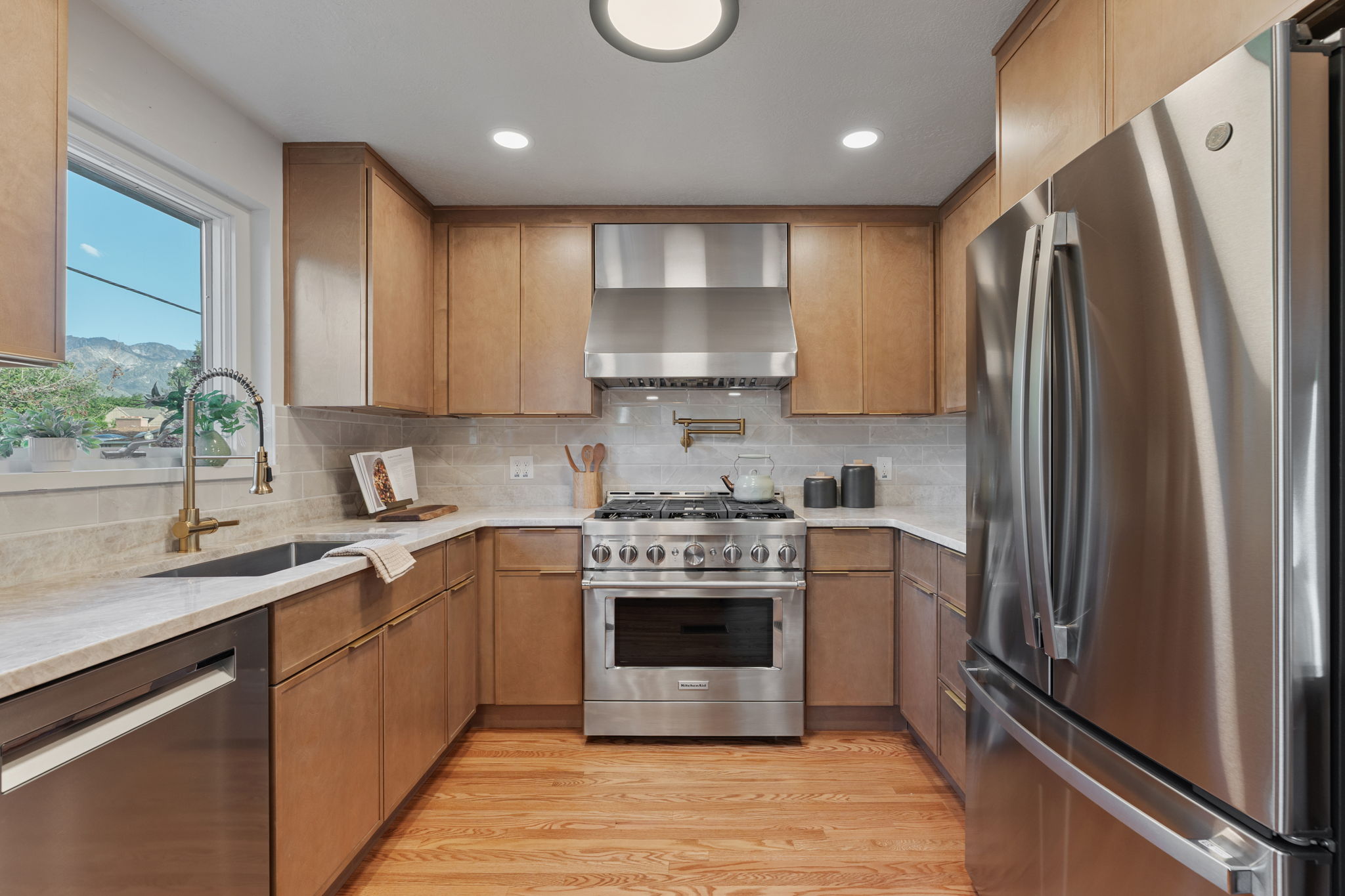 Kitchen featuring wood-finish cabinetry, stainless steel appliances, light countertops, and a tile backsplash