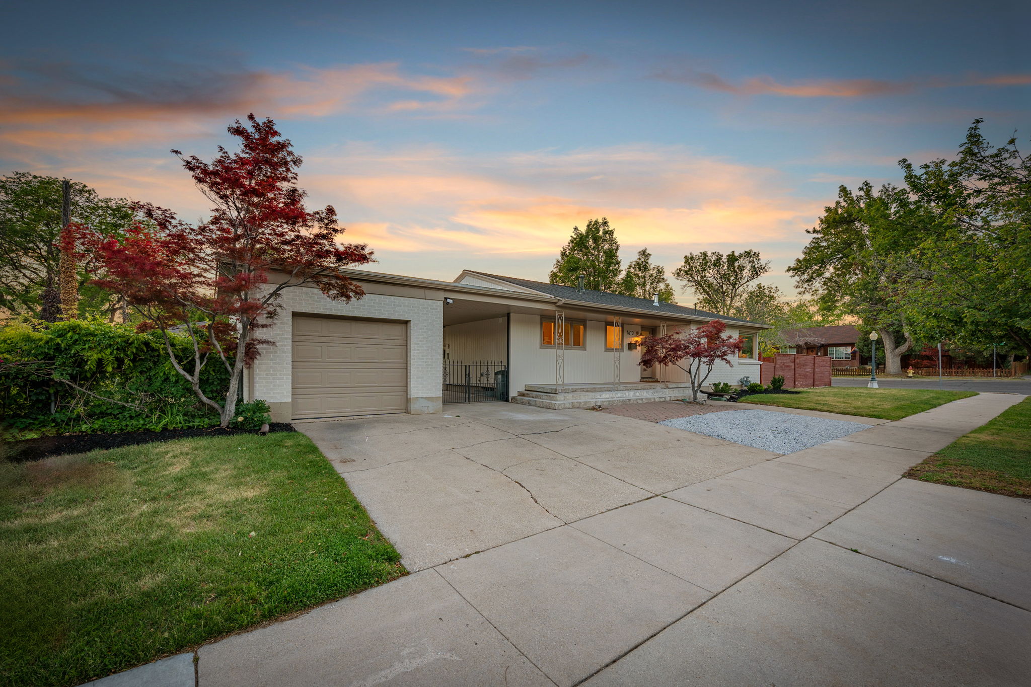 Ranch-style residence featuring a prominent attached garage with a tan door, a covered carport, and a concrete driveway