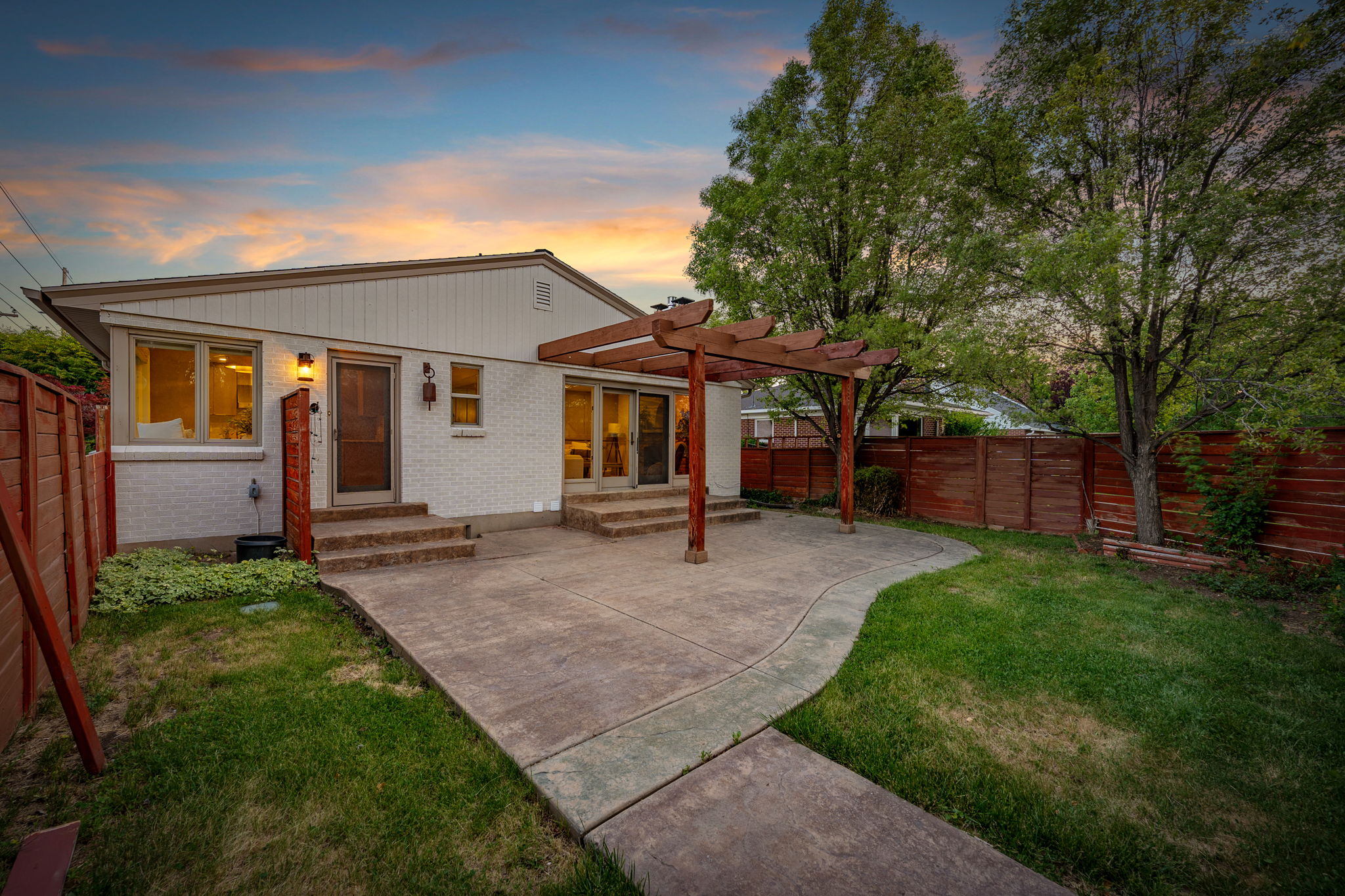 Expansive backyard featuring a concrete patio, a wood pergola, and a manicured lawn