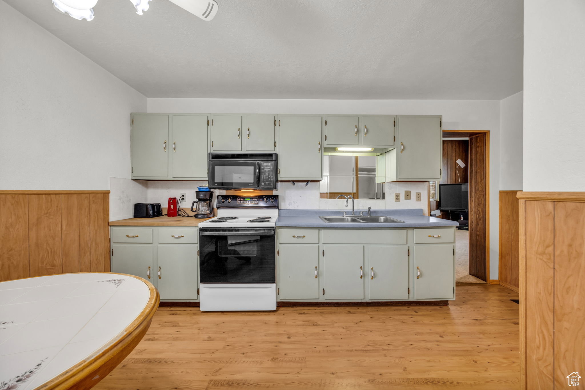Kitchen featuring wood-finish flooring, light-colored upper and lower cabinetry, laminate countertops, and wood paneling