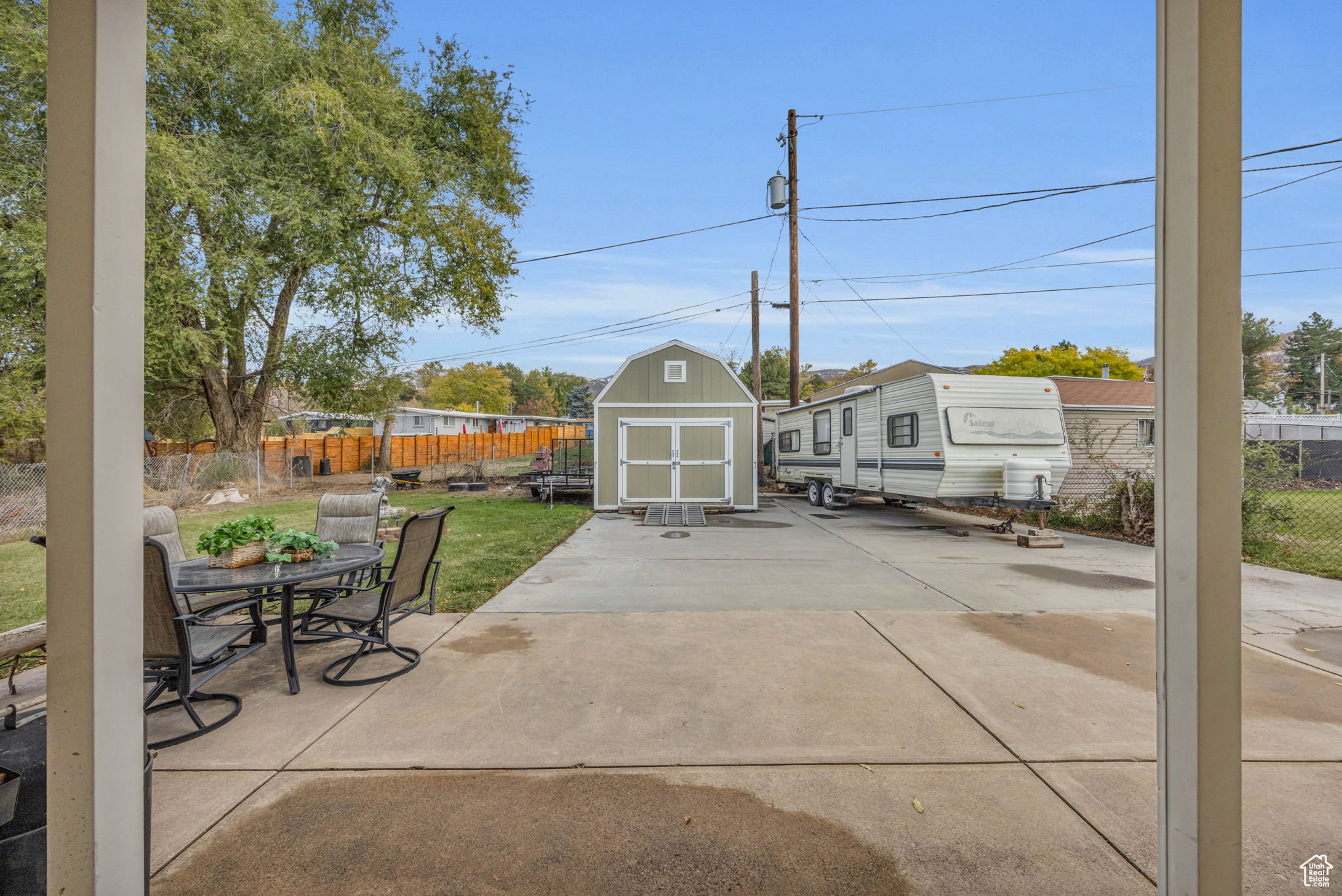 Concrete patio with a detached storage shed and expansive paved area