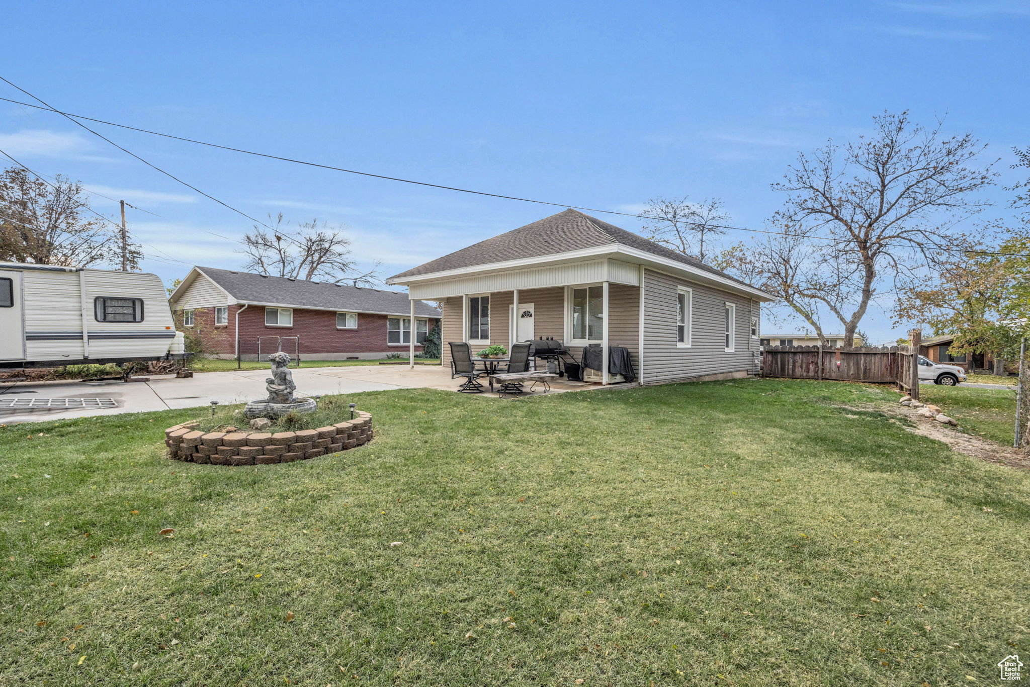 Expansive front yard featuring a manicured lawn, a decorative fountain within a brick-bordered bed, a covered front porch, and horizontal siding