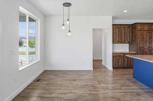 Open-concept area featuring wood-finish flooring, a modern three-light pendant fixture, and a large window