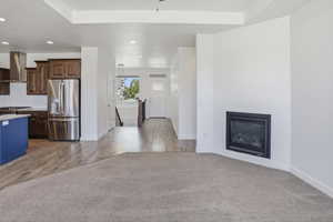 Spacious open-concept living area featuring an inset fireplace, recessed lighting, and a tray ceiling