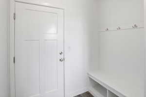 Entryway featuring a white paneled door with brushed nickel hardware, built-in white bench with storage cubbies, and a wall-mounted coat rack