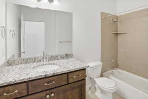 Bathroom featuring a dark wood-finish vanity with a light speckled countertop, an integrated sink, and a large wall-mounted mirror