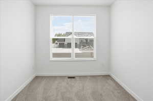 Bright room featuring a large window with white blinds, neutral-toned carpet, and white baseboards