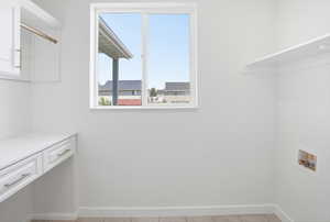 Functional utility space featuring a built-in white desk, upper cabinetry with hanging rod, and wall-mounted shelving