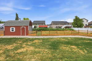 Expansive backyard featuring a red barn-style shed with white trim, a gabled roof, and a cupola