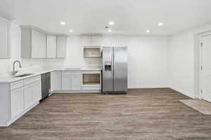 Kitchenette featuring light-toned cabinetry, stainless steel refrigerator, and wood-finish flooring