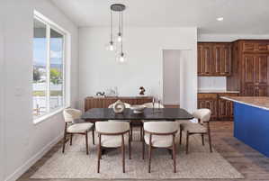 Dining area featuring a contemporary linear chandelier with clear glass globes, large window with white trim, and wood-finish flooring