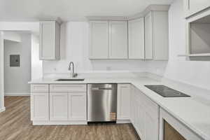 Contemporary kitchen featuring light-toned shaker cabinetry, undermount sink with gooseneck faucet, light-toned countertops, and stainless steel dishwasher