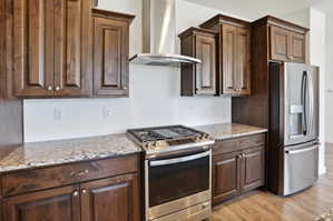 Kitchen featuring rich wood cabinetry, light-toned countertops, stainless steel appliances, a gas range, and wood-finish flooring