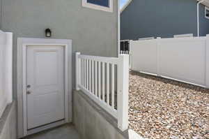 Side entry with a white paneled door, exterior wall light, and concrete landing