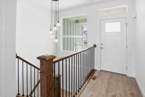 Entryway featuring wood-finish flooring, a white paneled door with frosted glass, and a transom window