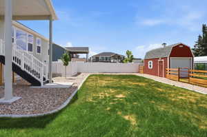 Expansive backyard featuring a manicured lawn, a detached red barn-style shed, and a white vinyl privacy fence