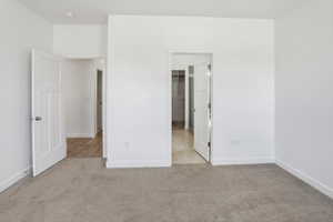 Neutral carpeted room featuring white walls, white trim, and two paneled interior doors