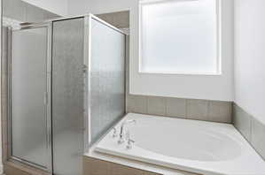 Built-in soaking tub with chrome fixtures, surrounded by neutral-toned tile