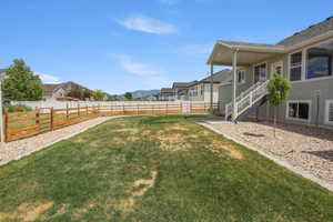 Expansive backyard featuring a large grass lawn, gravel beds, and a combination of wood and vinyl fencing