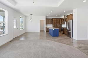 Open-concept living space featuring wood-finish flooring, recessed lighting, and a tray ceiling