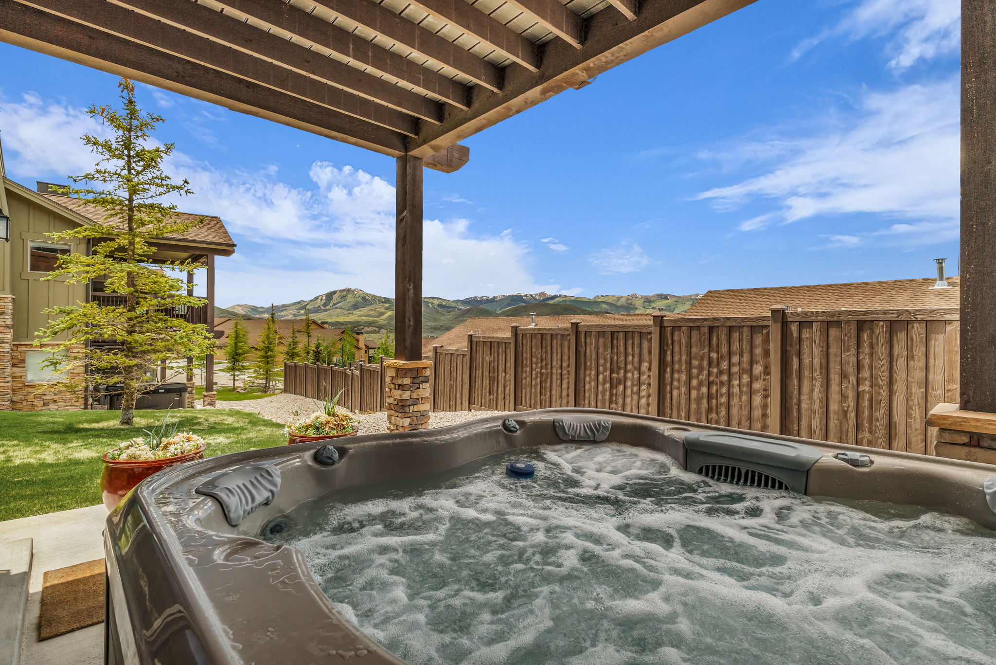 Outdoor spa with bubbling water, set beneath a wood pergola with stone-clad posts