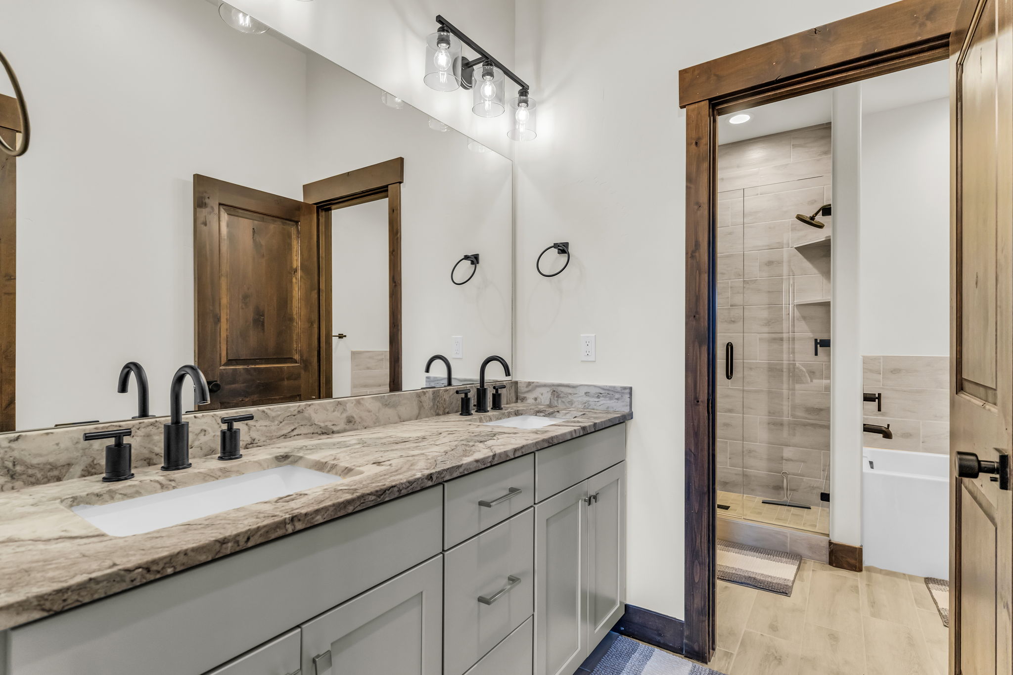 Bathroom featuring a dual vanity with a light-toned countertop, undermount sinks, and matte black fixtures