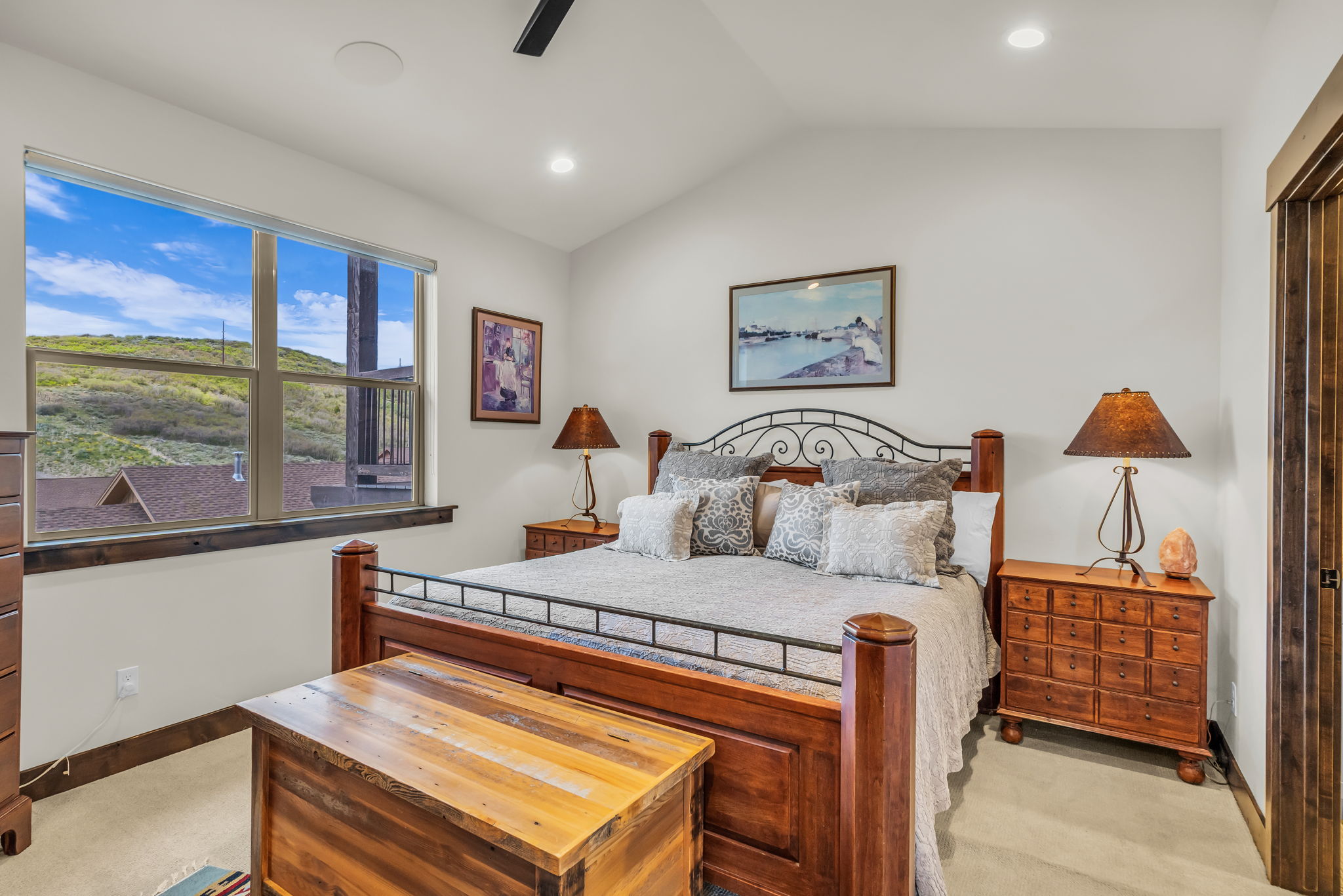 Spacious room featuring a large window with distant hillside scenery, a vaulted ceiling, recessed lighting, and a ceiling fan