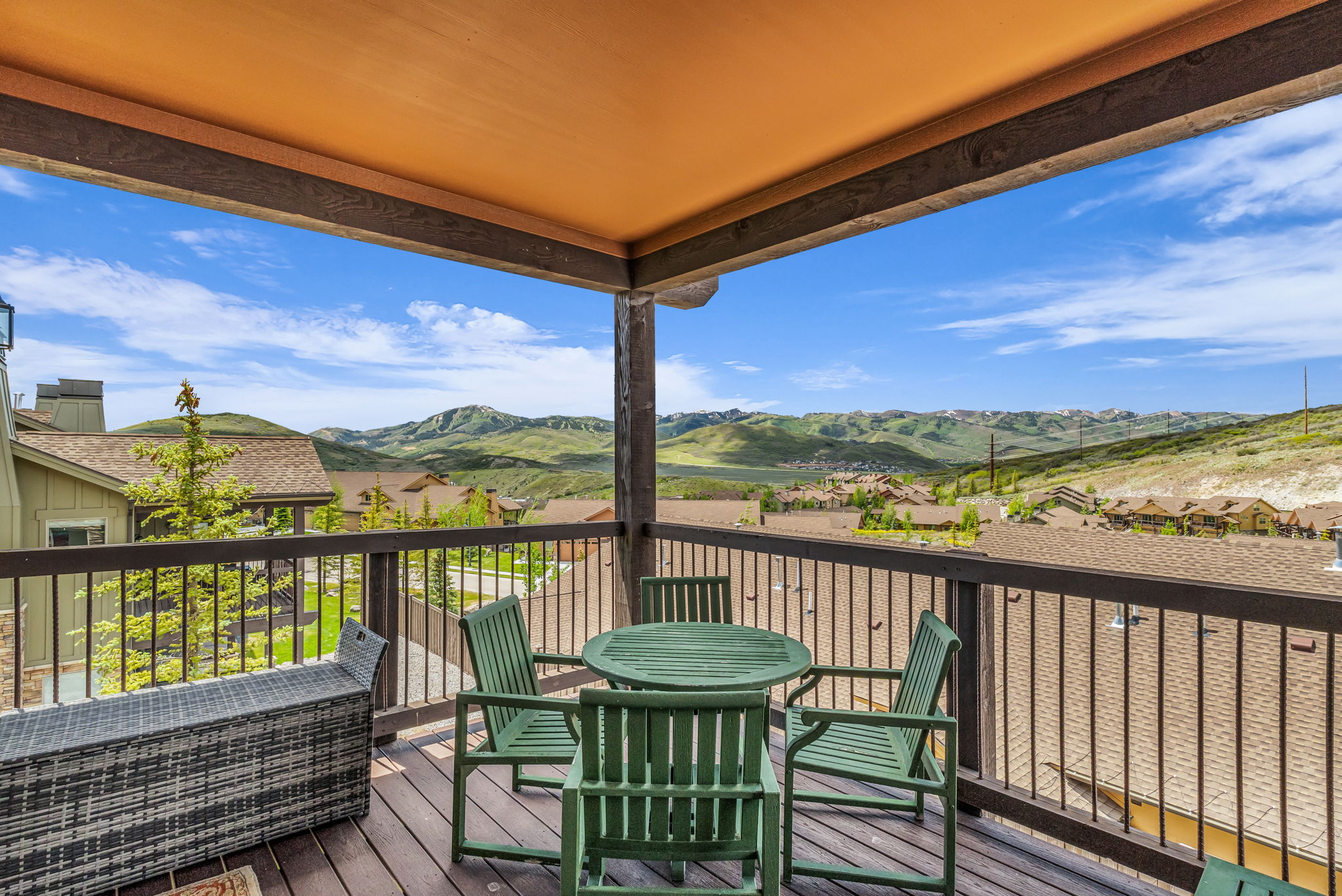 Covered outdoor deck with wood-finish decking and dark railing, offering expansive mountain scenery