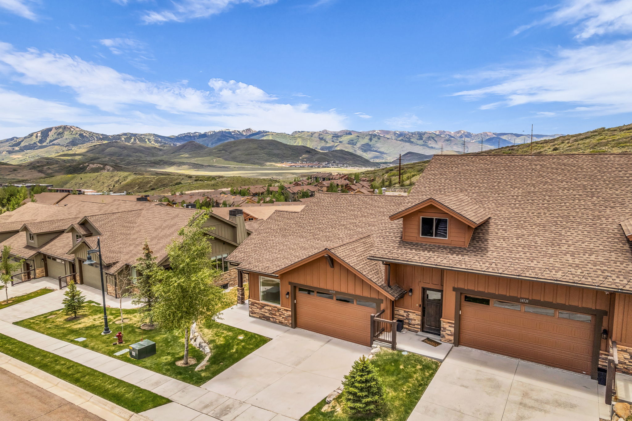 Townhome exterior featuring earth-toned siding, brown shingle roofing, and attached garages