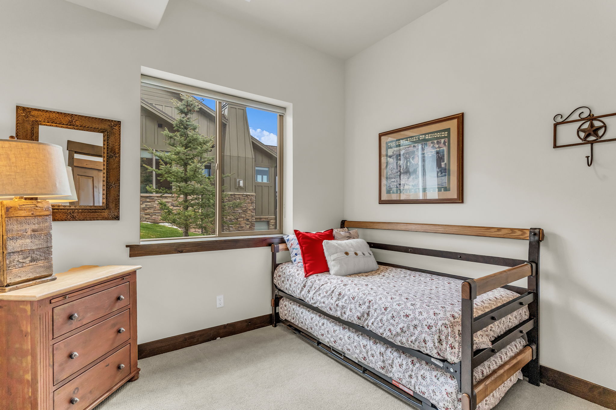 Bright interior space featuring a large window with exterior landscaping, light-toned walls, and wood-finish trim