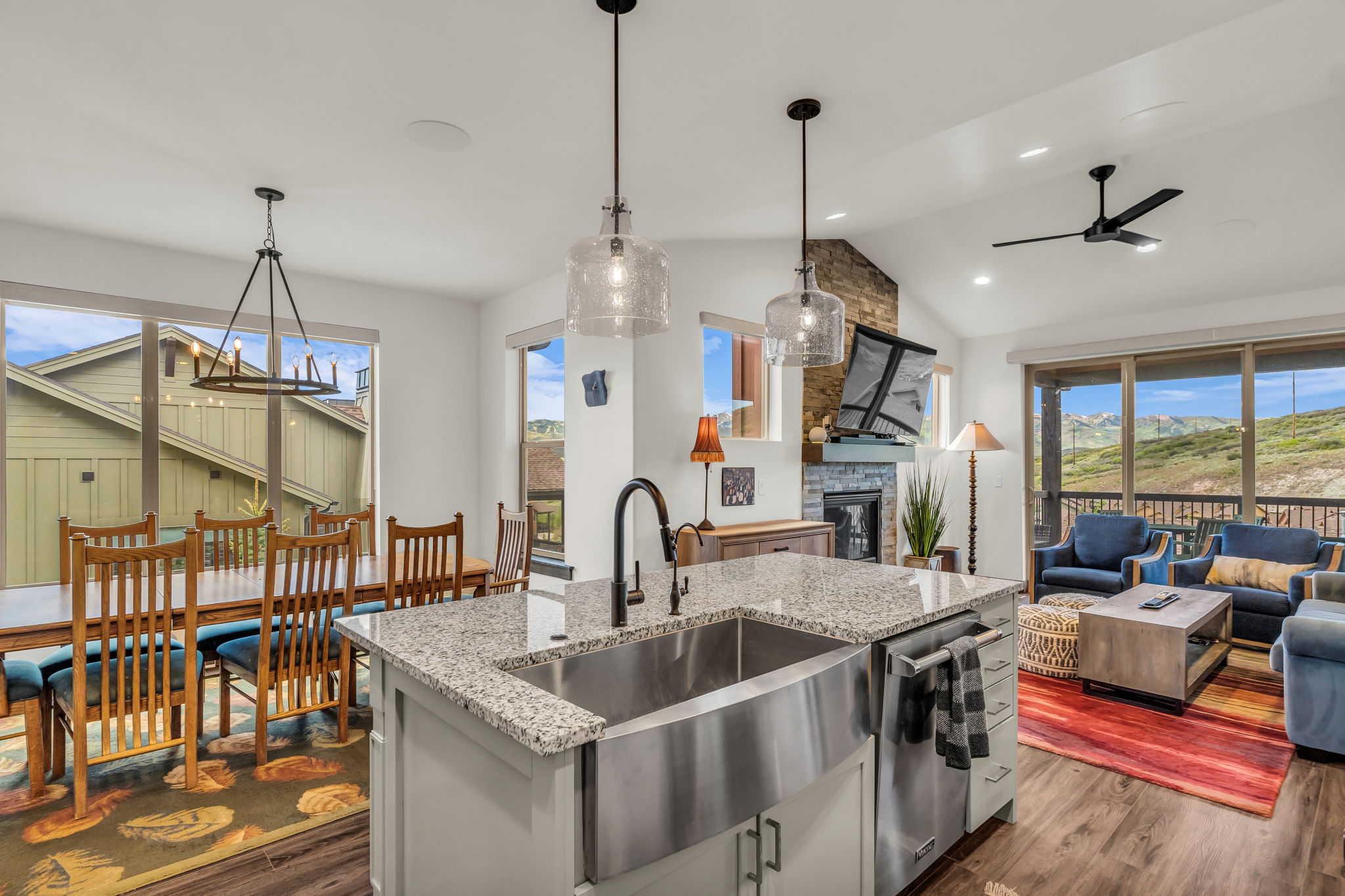 Kitchen island featuring a farmhouse sink, granite countertop, and pendant lighting
